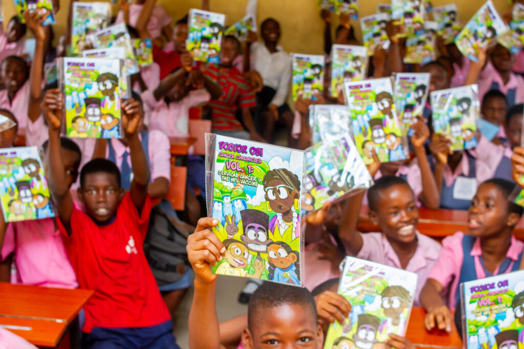 School children in Nigeria hold up a comic book that Global Oncology designed to help teach about HPV and cervical cancer.