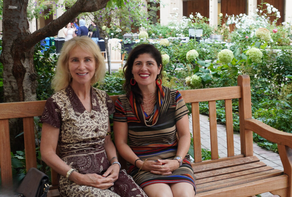 Dr. Barb Erny, left, and Dr. Desiree LaBeaud, right, are  seated together at an outdoor event, smiling broadly