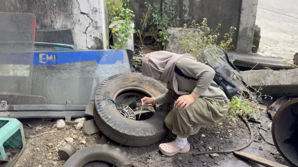 A researcher in Makassar samples stagnant water from a tire that could hold mosquito larvaeåç