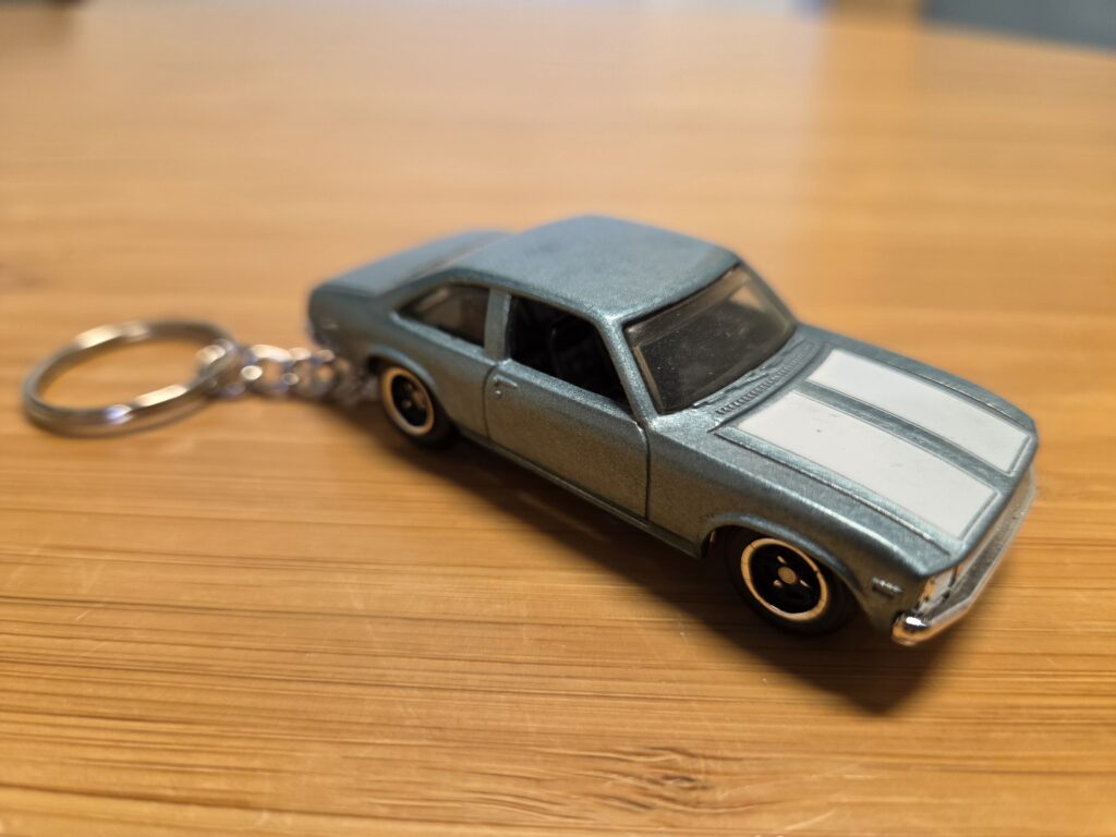 A keychain of a blue-green chevy nova on a table